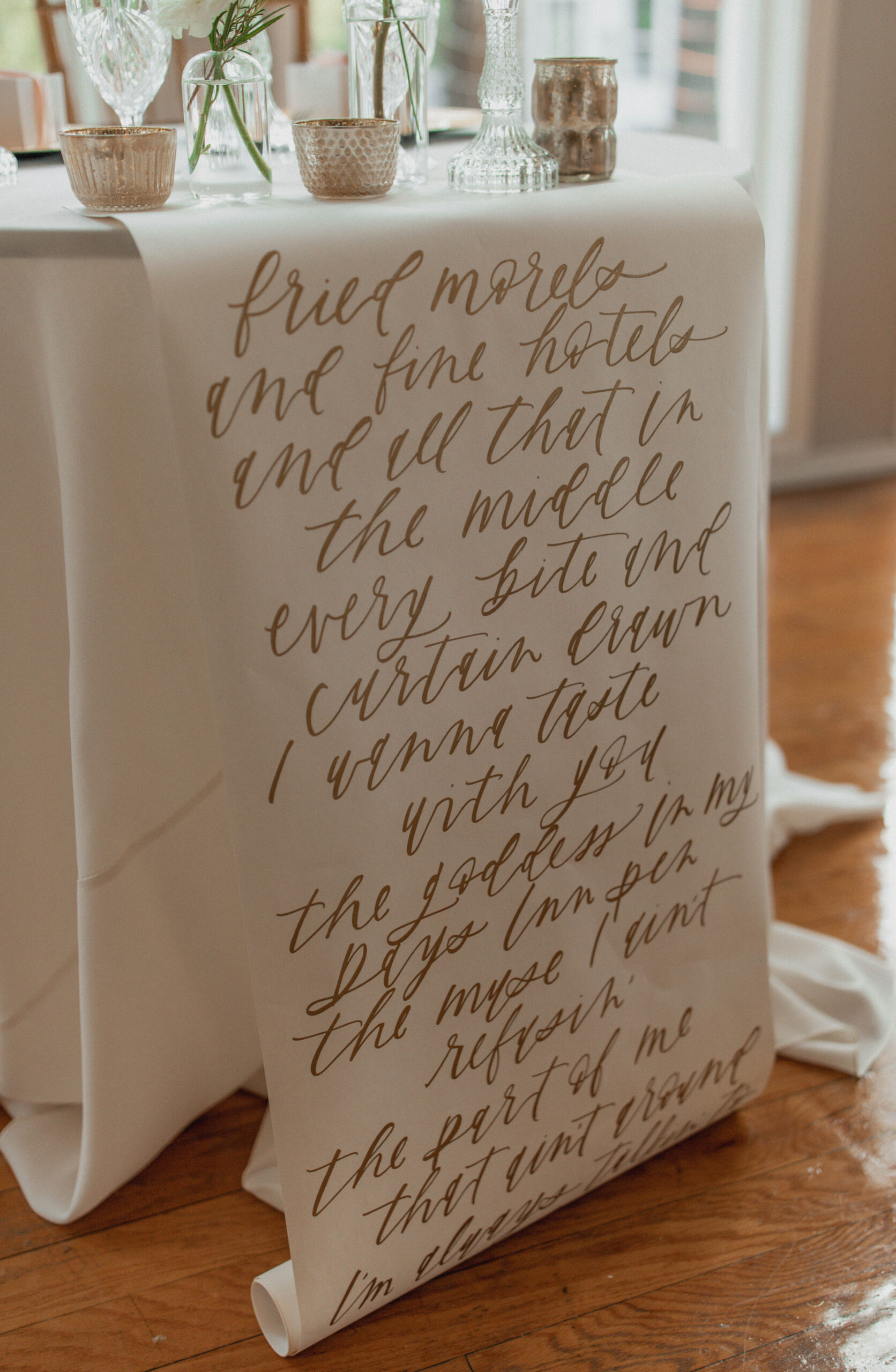 Hand written love quote table scroll at a sweetheart table during wedding reception.