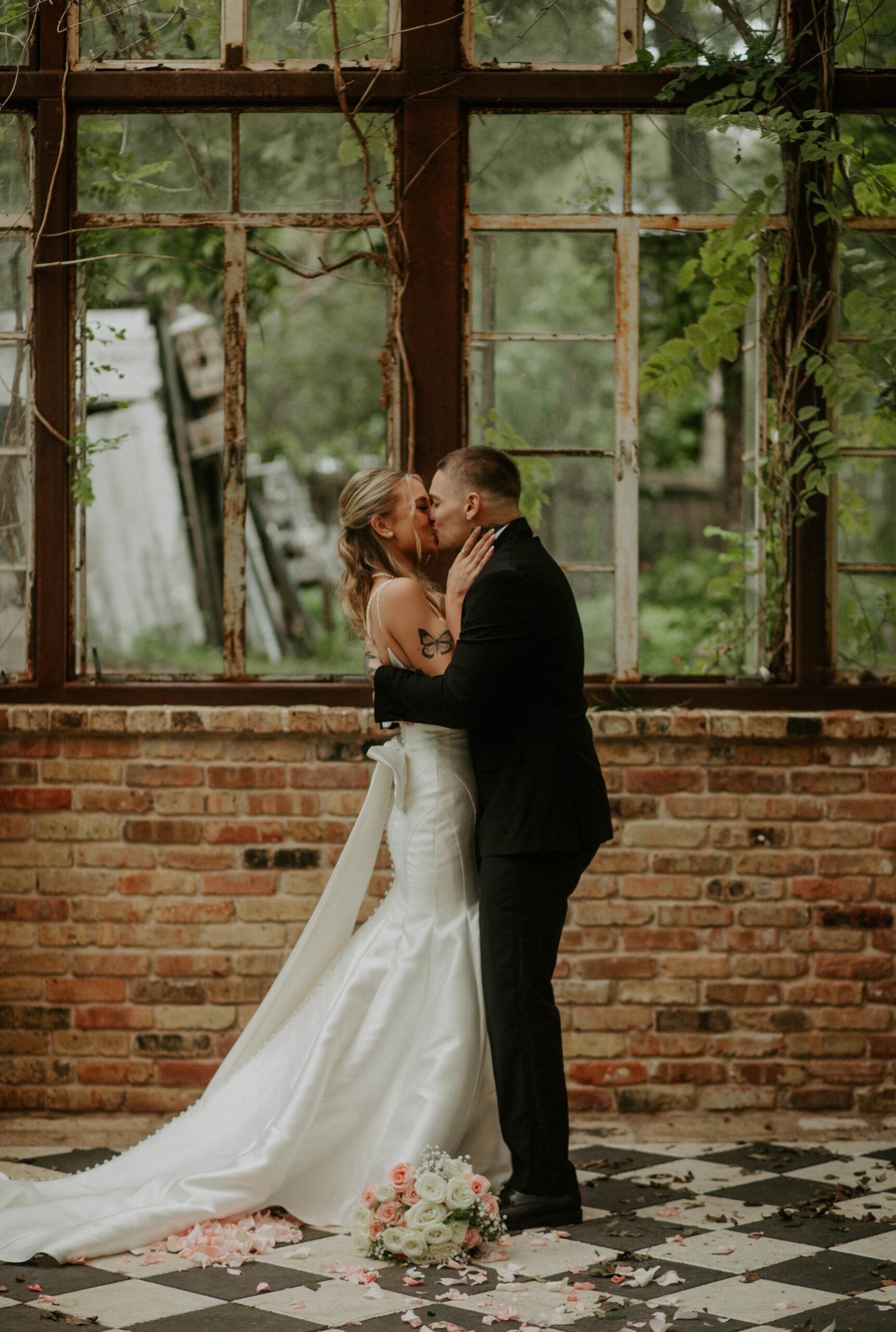 Bride and groom share a romantic kiss in front of the rustic window backdrop at Sekrit Theater in Austin. Perfect venue for intimate weddings and elopements.