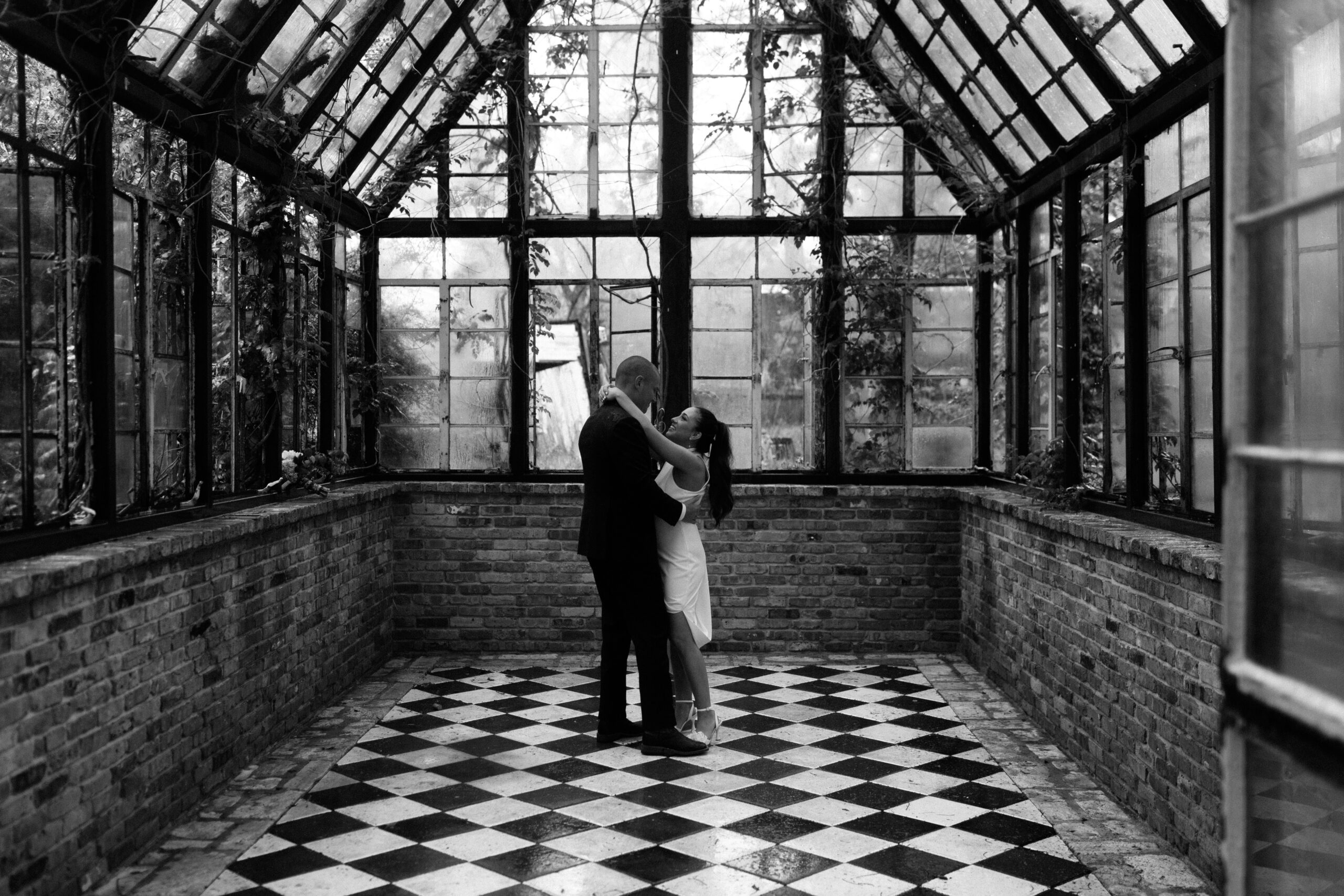 A couple sharing their first dance in a greenhouse with checkered floors.