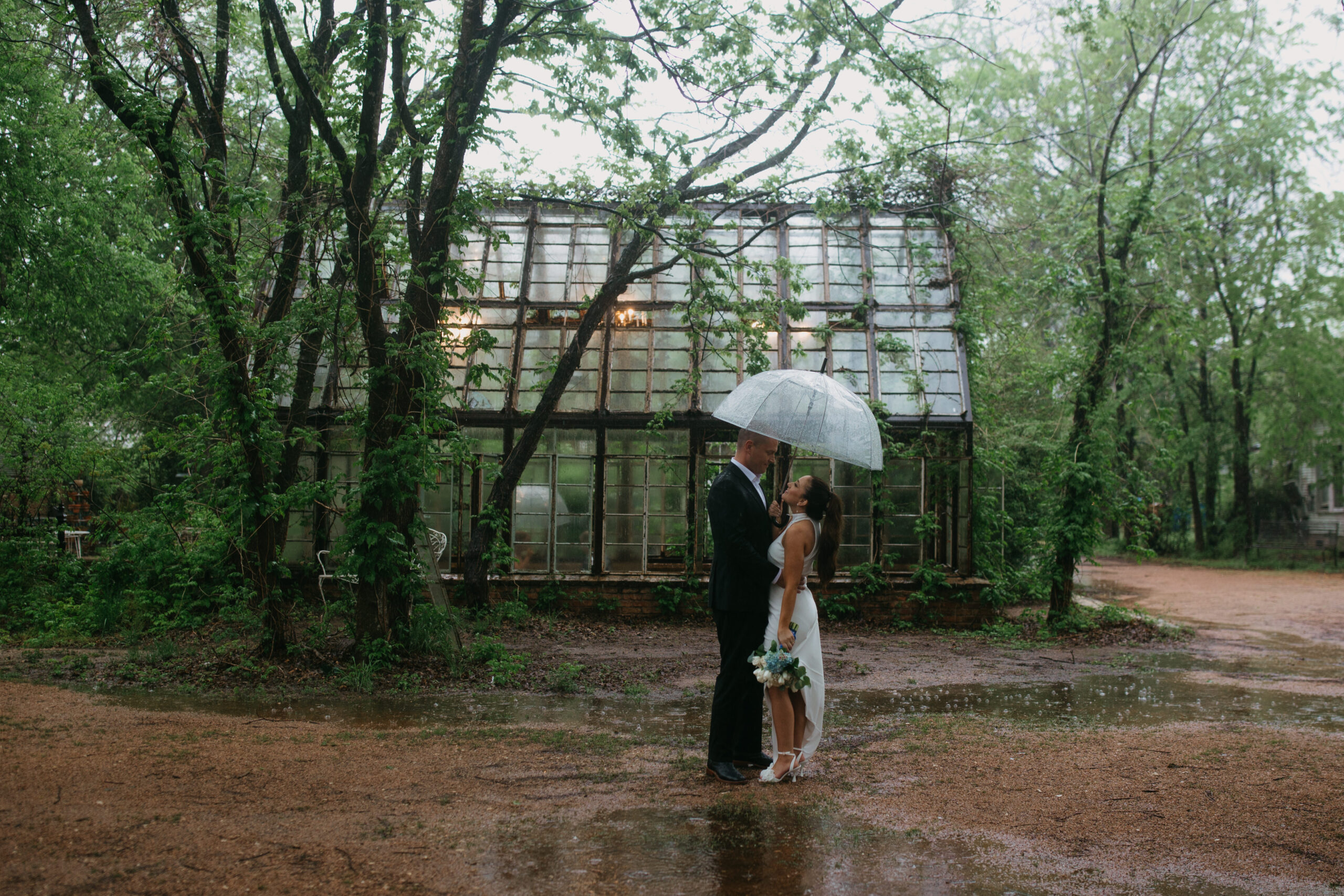 Groom and Bride sharing a hug under a shared umbrella at Sekrit Theater.