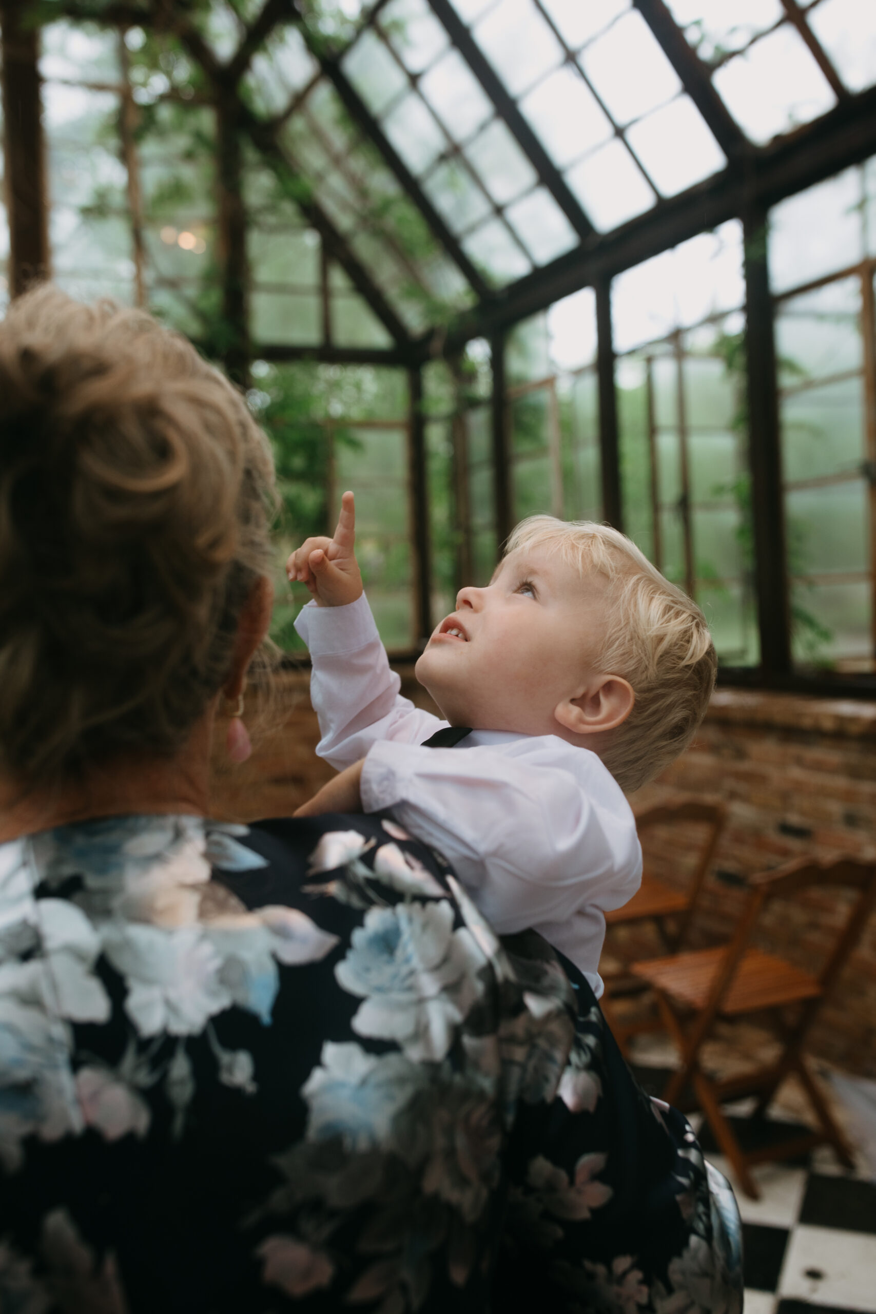 A child pointing to the roof of a greenhouse and smiling.