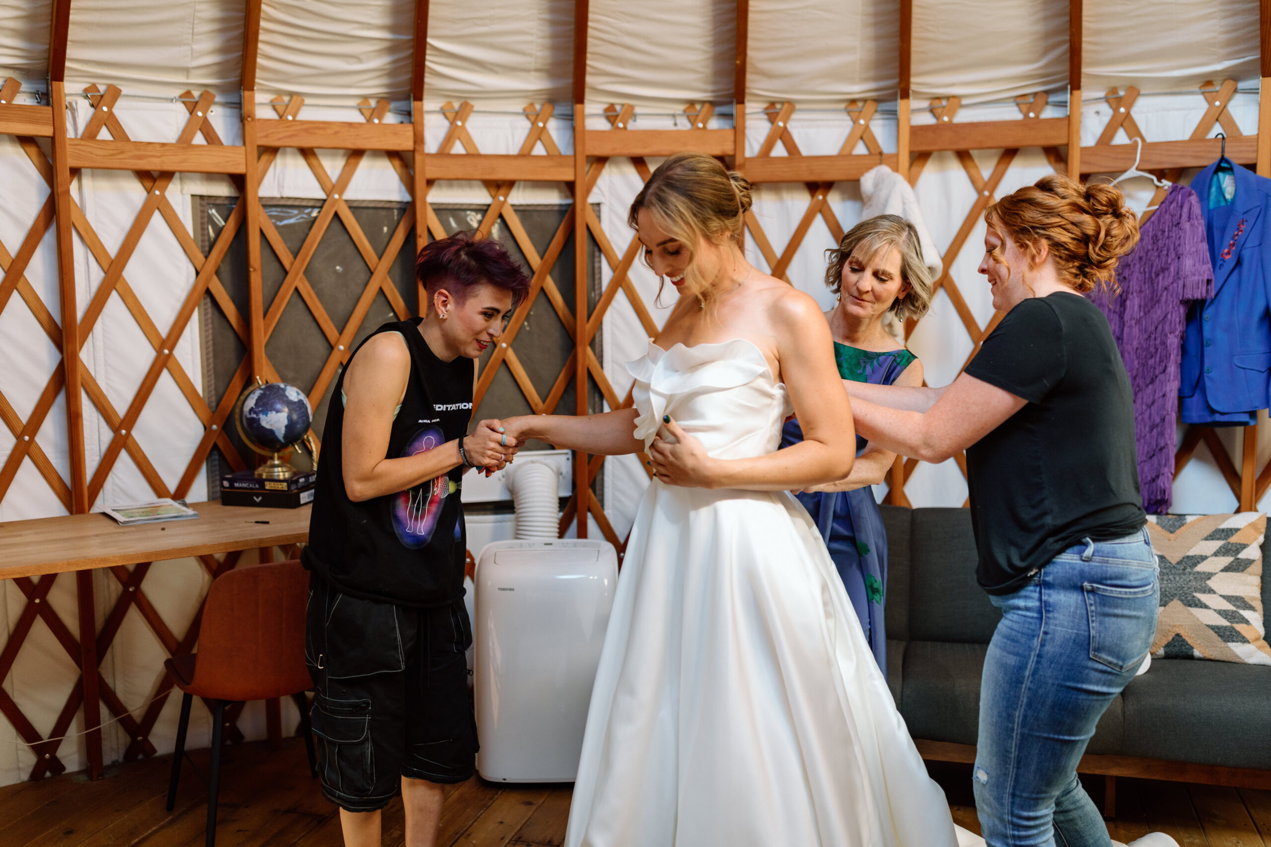 Friends and loved ones helping a bride into her wedding dress.
