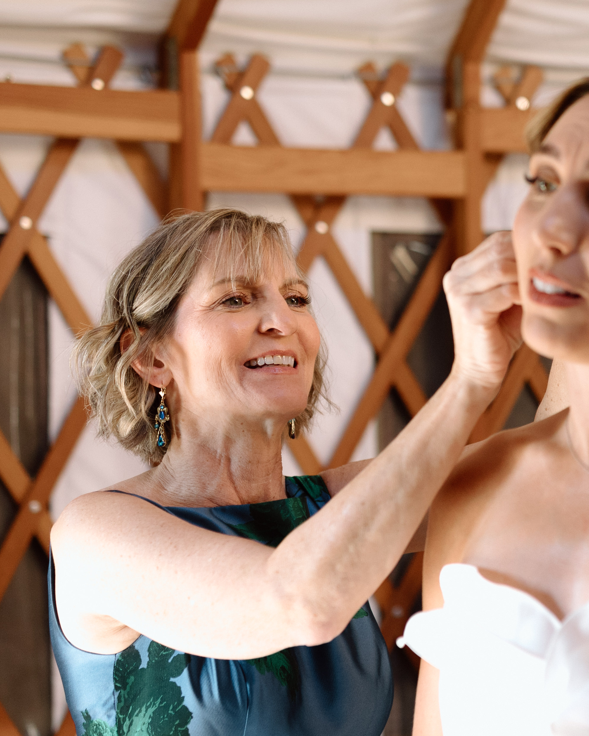 a mother helping her daughter put on her jewelry on their wedding day.